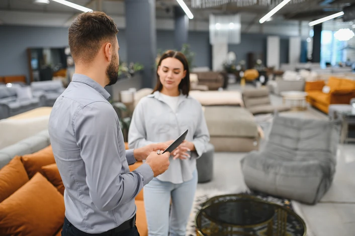 Couple détendu sur canapé gris moderne consultant tablette et smartphone dans salon contemporain