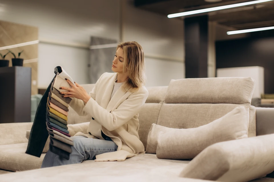 Une femme examine un matelas dans un magasin de mobilier, testant la fermeté en appuyant sa main sur la surface